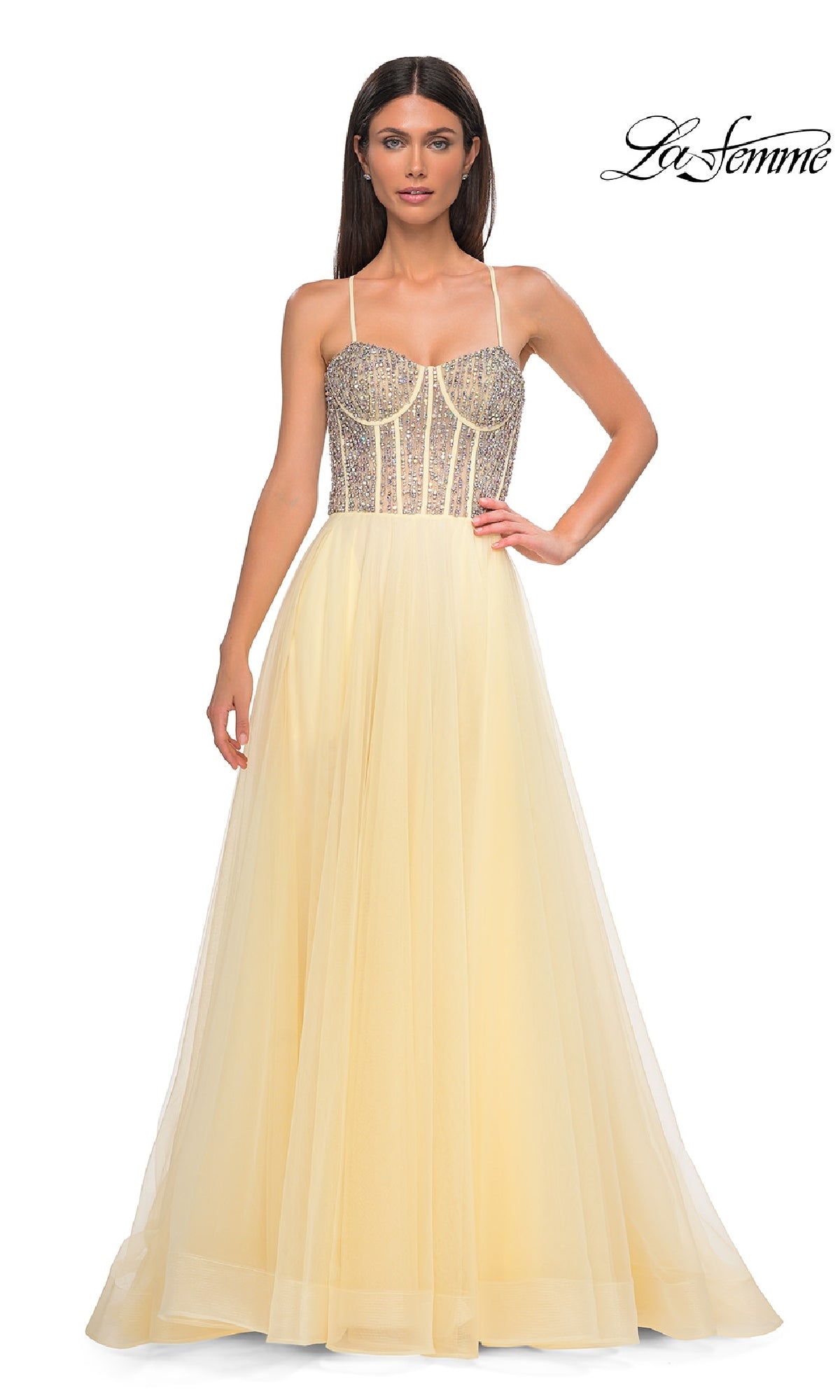 Woman in a Beaded-Corset Long Prom Dress (La Femme 32703) with a sheer, rhinestone-embellished bodice and thin straps, posing against a white background. 