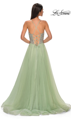A woman is wearing the Beaded-Corset Long Prom Dress La Femme 32703, featuring a light green tulle skirt, fitted bodice with lace-up open back, thin shoulder straps, and an elegant floor-length a-line silhouette.