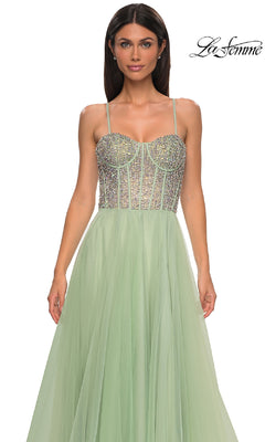 A woman models the La Femme 32703 Beaded-Corset Long Prom Dress—a light green evening gown with rhinestone beading, thin straps, and a flowing skirt—standing against a plain white background.
