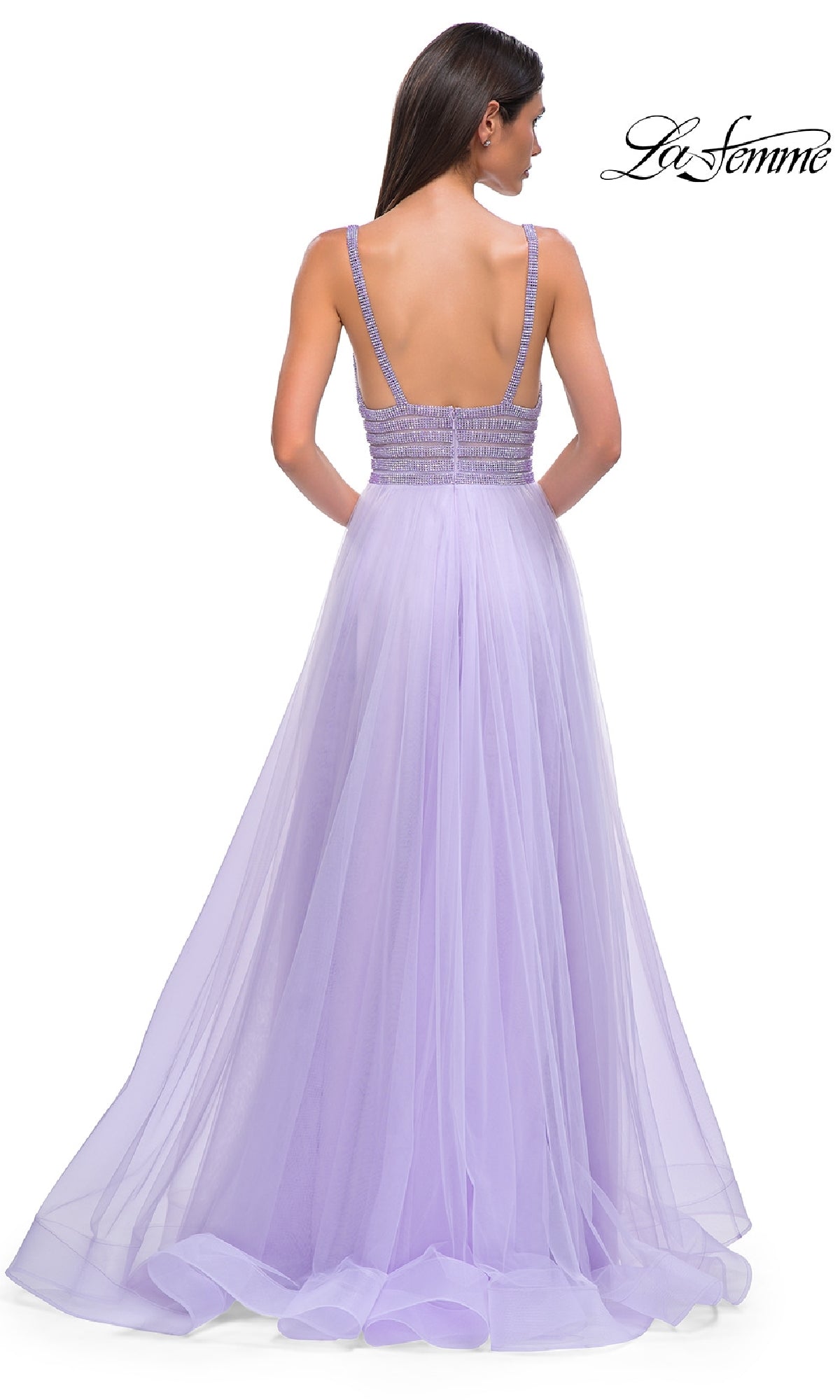 Woman in a sleeveless, floor-length lavender La Femme 32714 prom ball gown with an open back, rhinestone-bodice, and sheer tulle skirt stands facing away. 