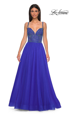 A woman models the La Femme 32714 prom ball gown—a royal blue, A-line dress with thin straps and a sparkling rhinestone-bodice—against a white background.