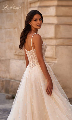 A woman stands outdoors, looking over her shoulder in the Polka-Dot Long Prom Ball Gown: La Femme 32716—a white, corset-style sleeveless dress with a polka-dot tulle skirt.