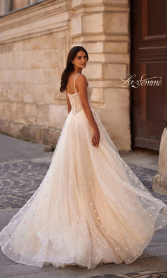 A woman in a Polka-Dot Long Prom Ball Gown: La Femme 32716 stands outdoors on a cobblestone path, looking over her shoulder.