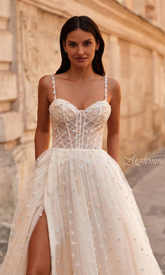 Woman wearing the La Femme 32716 Polka-Dot Long Prom Ball Gown, a sleeveless corset-style dress with thin straps and a thigh-high slit, standing outdoors against a stone wall.