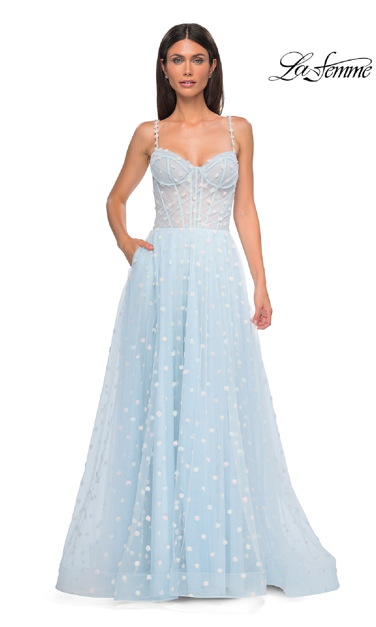 A woman in a light blue La Femme 32716 polka-dot long prom ball gown, showcasing a fitted bodice, sheer panels, thin straps, and elegant floor-length style with white polka dot details.