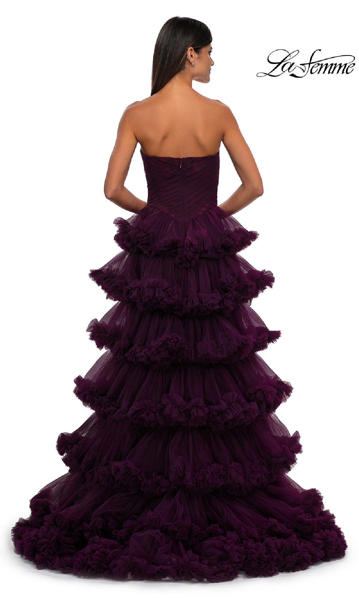 A woman, seen from behind against a white background, wears the Strapless Ruffled Prom Ball Gown: La Femme 32721—a floor-length deep purple tiered ruffle dress; 