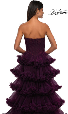 A woman with long dark hair models the La Femme 32721 Strapless Ruffled Prom Ball Gown, a purple tiered dress with elegant ruffled layers, shown from the back against a white background.