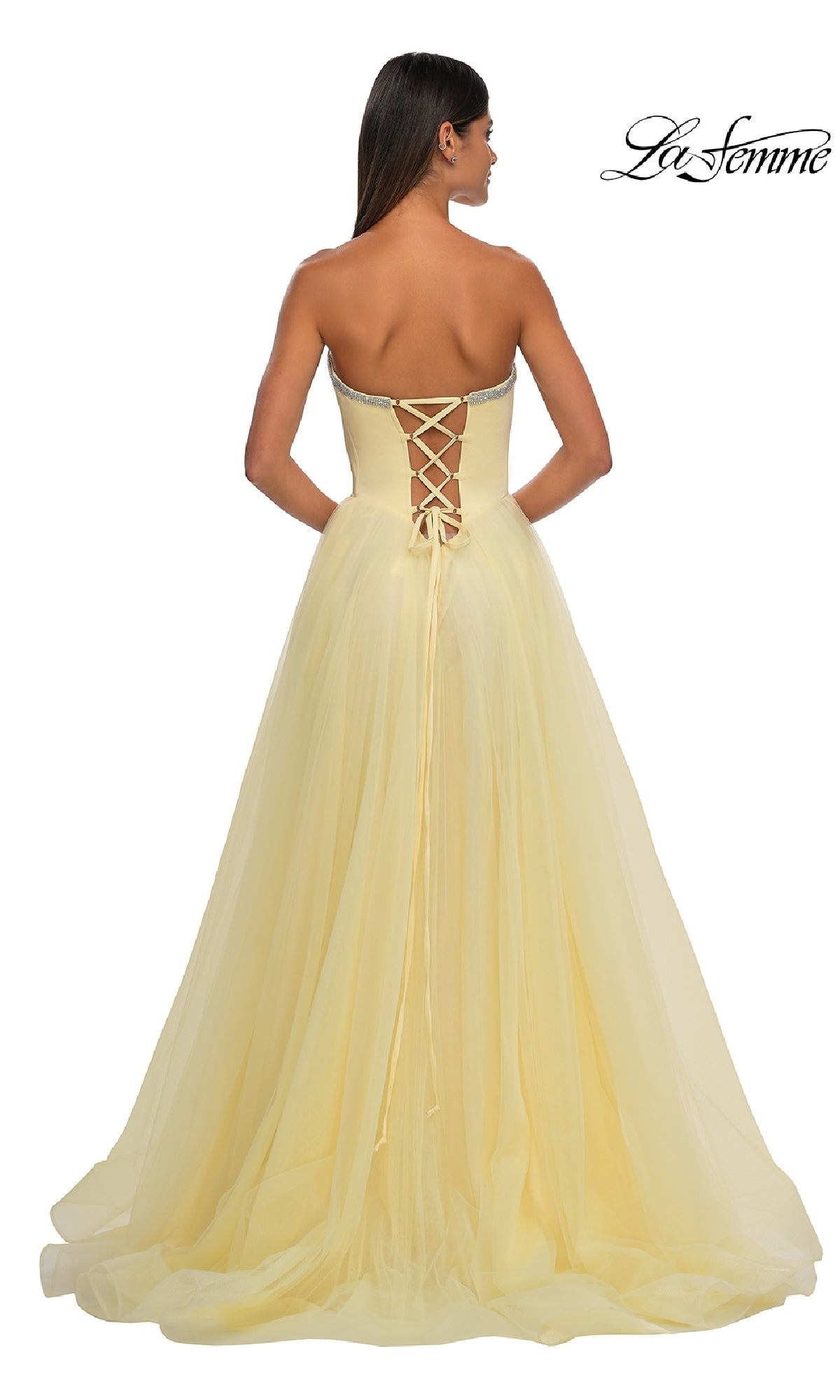 A woman faces away wearing the Strapless Long Prom Ball Gown: La Femme 32731, featuring a sweetheart neckline and lace-up back; 