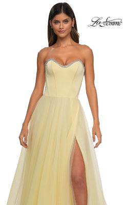 A woman wears the La Femme 32731 strapless long prom ball gown, a light yellow dress with a sweetheart neckline, silver trim, thigh-high slit, fitted bodice, and flowing tulle skirt for an elegant formal look.