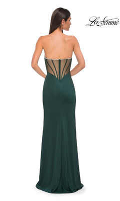 A woman wearing the La Femme 32733 bead-trimmed strapless prom dress—a floor-length dark green gown with a sweetheart neckline, sheer structured back panel, and beaded accents, shown from behind.