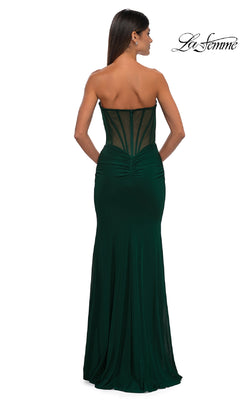 A woman models the La Femme 32734 Cut-Out Long Strapless Prom Dress—an elegant, floor-length dark green gown with a sheer back panel and ruched details—against a white background.