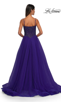 A woman in the La Femme 32754 Beaded-Bodice Long Prom Dress, deep purple with rhinestone details, thin straps, and a fitted back bodice flows into a full tulle skirt for an elegant formal look.