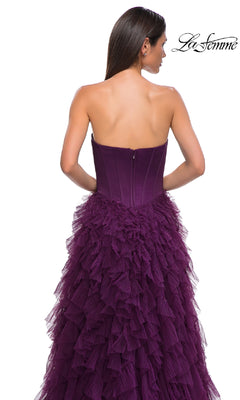 Woman modeling the La Femme 32760: a strapless long ruffled prom dress with a deep purple corset-style bodice and layered tulle skirt, shown from the back against a white background.