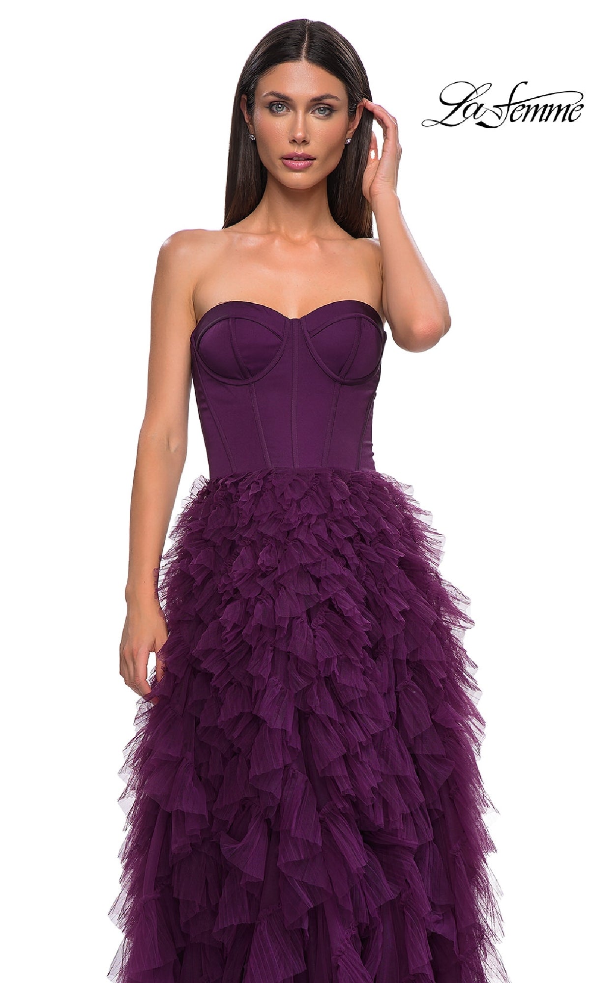 A woman wears the Strapless Long Ruffled Prom Dress: La Femme 32760 in deep purple, with a corset-style bodice and layered skirt. The 