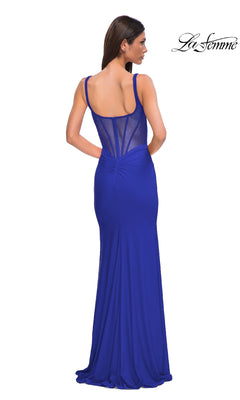 A woman wears the Plunging V-Neck Long Prom Dress: La Femme 32763 in royal blue, with a sleeveless design, sheer back panel, floor-length skirt, and subtle ruching—an elegant pick for formal events.