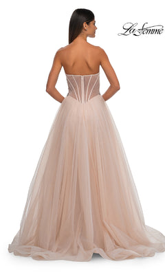 A woman is shown elegantly from the back in the Strapless Long Prom Ball Gown: La Femme 32767, a blush pink dress with a sheer beaded corset bodice and a flowing tulle skirt.