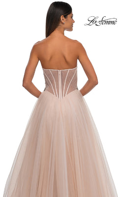 A woman wearing the Strapless Long Prom Ball Gown: La Femme 32767, featuring a sheer beaded corset bodice and flowing tulle skirt, is photographed from the back against a white background.
