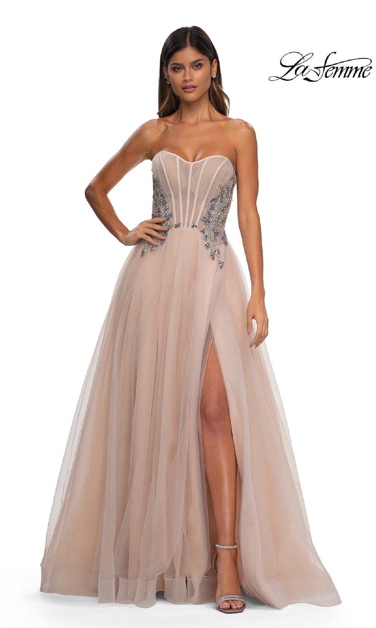 A woman models the Strapless Long Prom Ball Gown: La Femme 32767, featuring a tulle skirt, beaded corset bodice, embellished details, and high slit, standing against a white background.