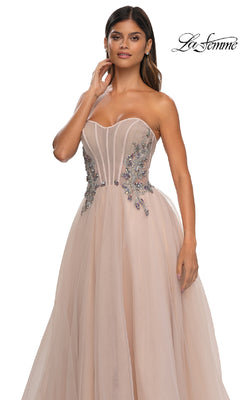 A woman stands against a white background wearing the La Femme 32767 Strapless Long Prom Ball Gown in blush, featuring floral bodice embellishments and an elegant A-line silhouette.