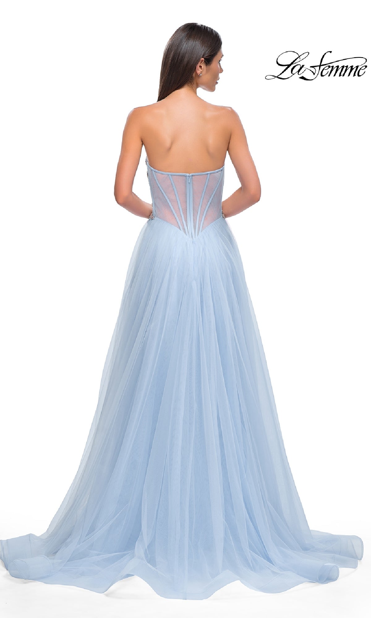 A woman stands with her back to the camera in a light blue tulle Strapless Long Prom Ball Gown, La Femme 32767, featuring a semi-sheer corset back. The 