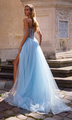 A woman in the La Femme 32767 strapless long prom ball gown with a beaded corset bodice stands outdoors on a stone path by an ornate building.