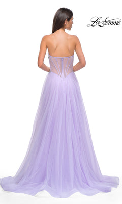 A woman stands with her back to the camera in the La Femme 32767, a strapless long prom ball gown featuring a floor-length lavender tulle skirt and sheer beaded corset bodice. The "La Femme" logo appears in the top right corner.