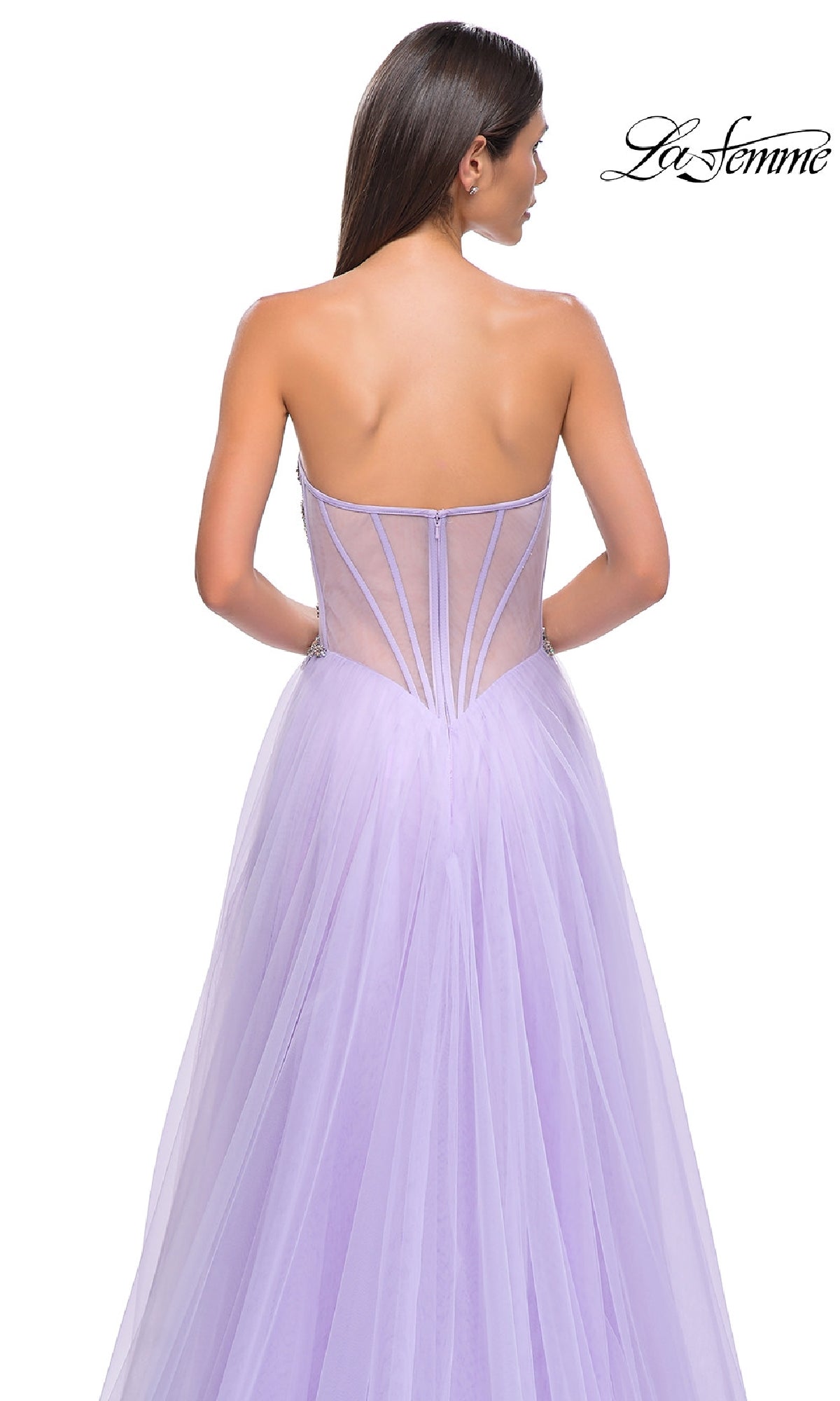 A woman in the Strapless Long Prom Ball Gown: La Femme 32767, a lavender tulle A-line gown with a sheer beaded corset back, is photographed from behind against a white background.