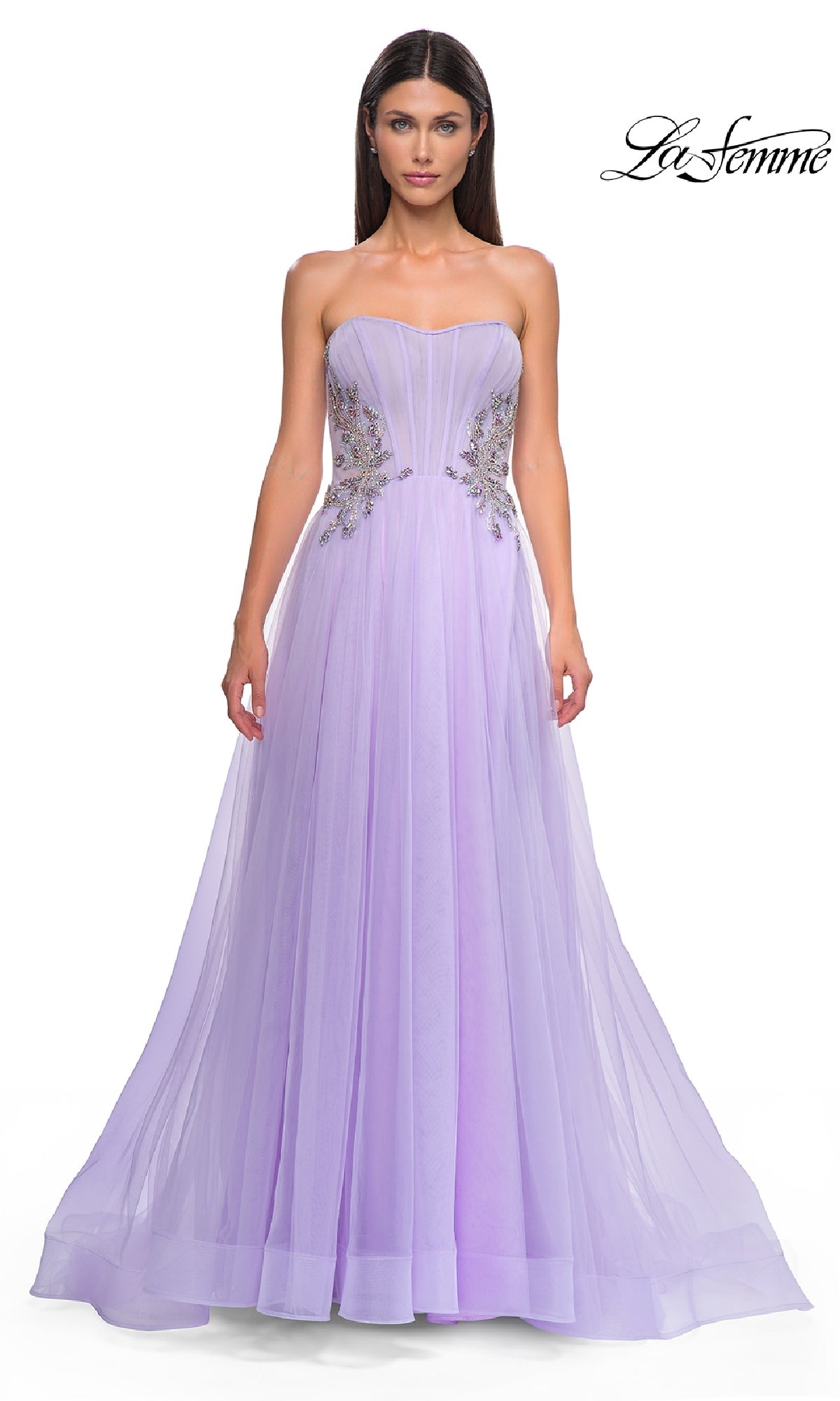 A woman wears the Strapless Long Prom Ball Gown: La Femme 32767, a floor-length lavender dress with floral-embellished bodice, standing against a plain white background.