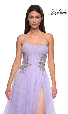 A woman models the Strapless Long Prom Ball Gown: La Femme 32767 in lavender, featuring jeweled embellishments and a thigh-high slit, against a white background.