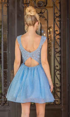 A woman with blonde hair in a bun wears the Cap-Sleeve Glitter Tulle Homecoming Dress 3276 in light blue, featuring lace accents and an open back, while standing before ornate black double doors.