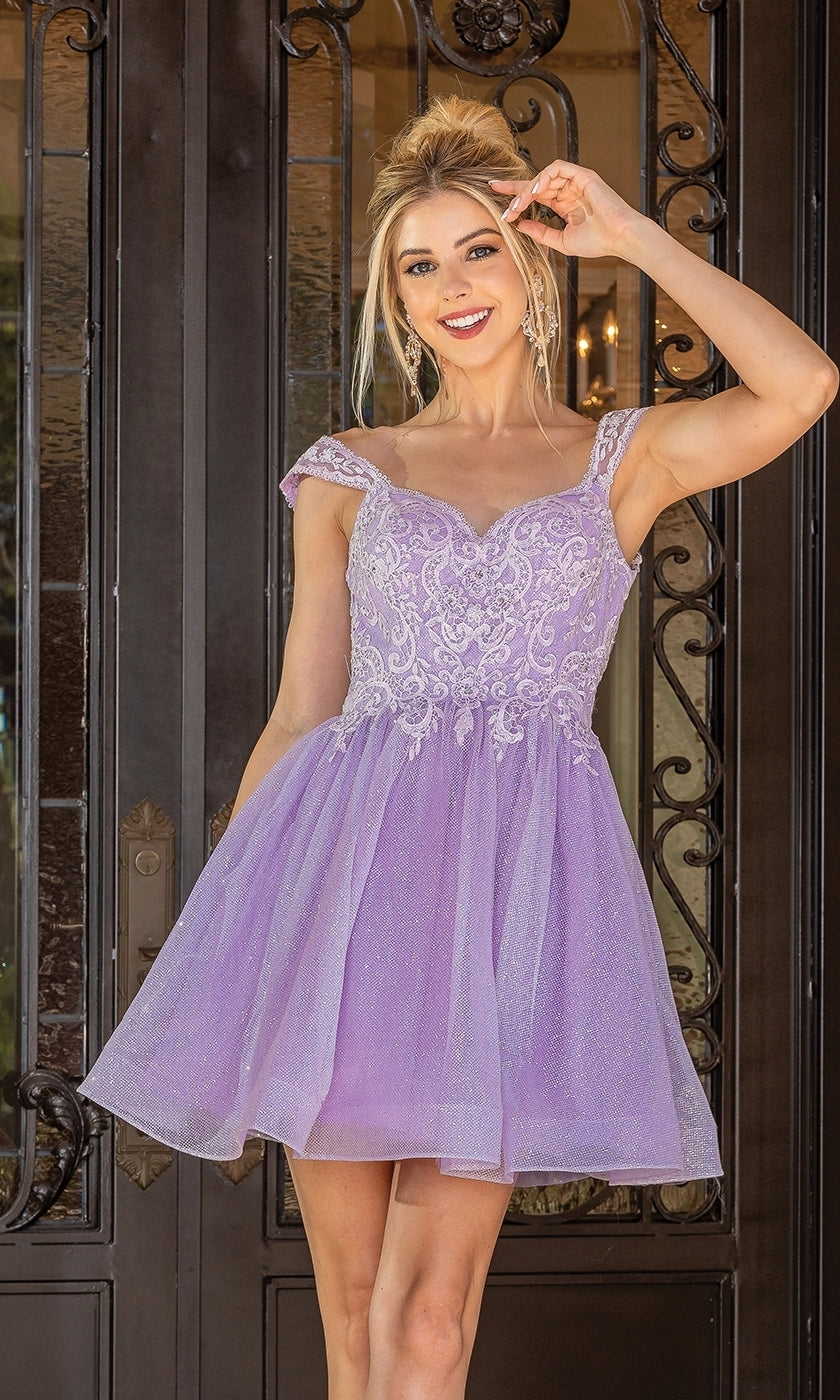 A woman in the Cap-Sleeve Glitter Tulle Homecoming Dress 3276 stands smiling before ornate black iron doors, her hand near her ear.