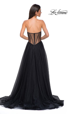 A woman wearing the La Femme 32771 black strapless long prom dress, featuring a sweetheart neckline, sheer corset-style back, and flowing tulle skirt, stands with her back to the camera.