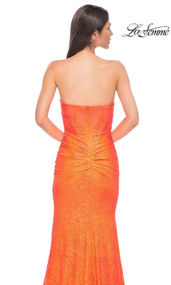 A woman models the Strapless Long Beaded Prom Dress: La Femme 32773 in orange, featuring a lace design, center ruching, and shown from the back. The "La Femme" logo appears in the top right corner.