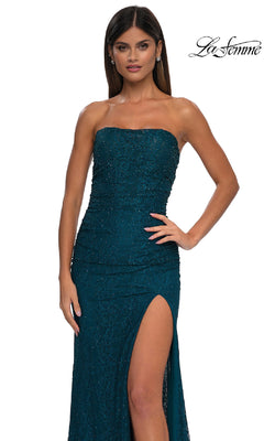A woman poses with one hand on her hip in a strapless, dark teal La Femme 32773 prom dress featuring sequins and a thigh-high slit, set against a plain background.