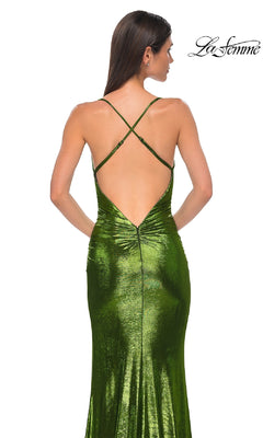 Woman wearing the Slinky Long Metallic Prom Dress: La Femme 32782, featuring shiny green fabric, crisscross straps, and a low open back. She stands against a white background with the "La Femme" logo in the top right corner.