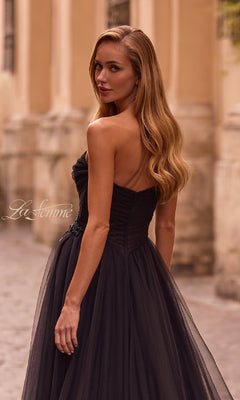 A woman in the La Femme 32789 strapless long prom ball gown with a sweetheart bodice and rhinestone floral detail stands outdoors, her long, wavy hair flowing as she glances over her shoulder.