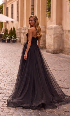 A woman wearing the La Femme 32789 Strapless Long Prom Ball Gown with a sweetheart bodice stands on a cobblestone street, glancing over her shoulder.