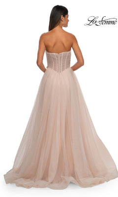 A woman in the La Femme 32789 strapless long prom ball gown stands with her back to the camera. The light pink tulle dress flows to the floor and features a fitted sweetheart bodice for timeless elegance.