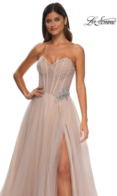 A woman wears the Strapless Long Prom Ball Gown: La Femme 32789, featuring a blush tulle skirt, sweetheart bodice, high slit, and rhinestone floral waist detail. The La Femme logo is shown in the top right corner.