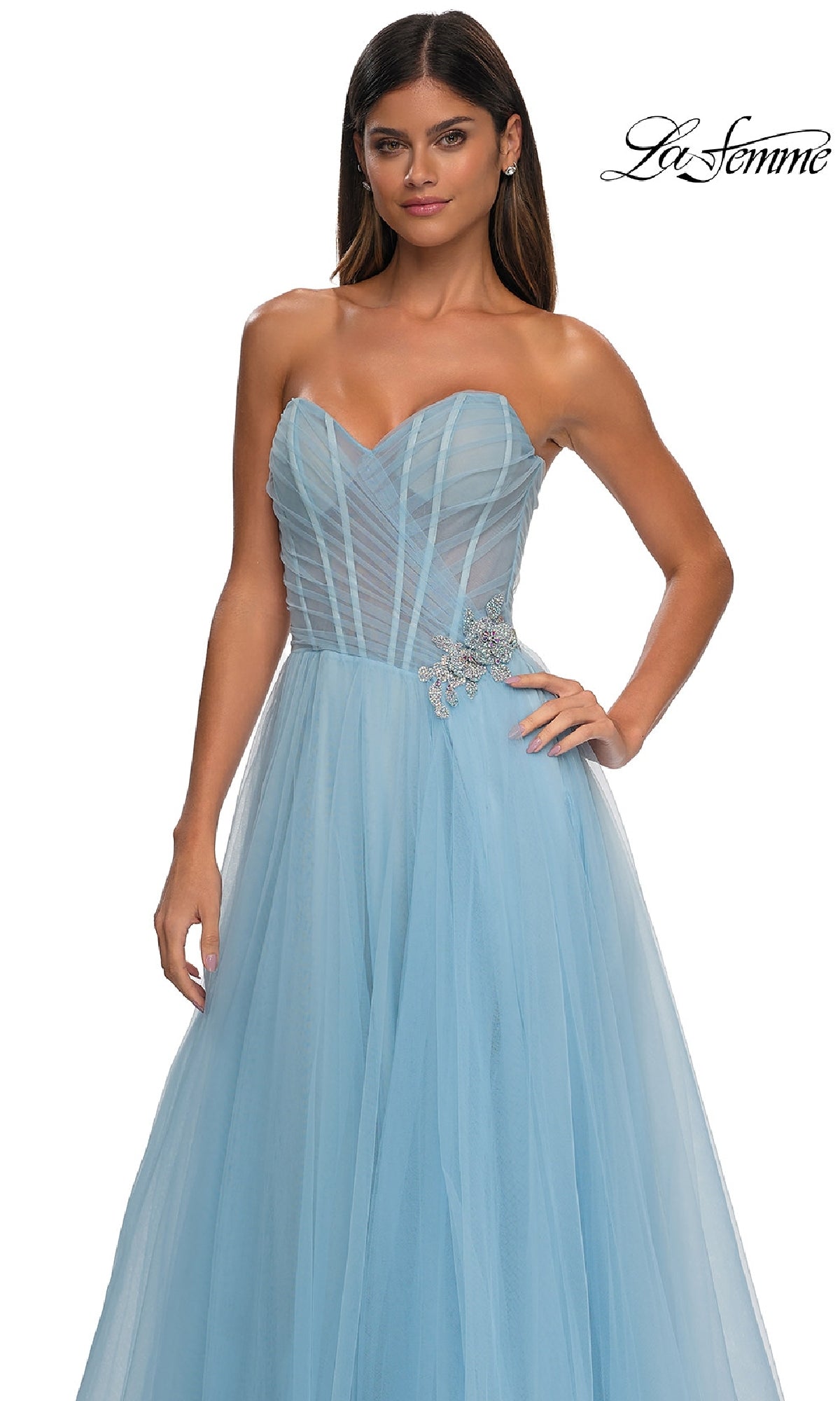 Woman in the La Femme 32789 strapless long prom ball gown, featuring light blue tulle, a sweetheart bodice, and rhinestone floral waist detail, standing against a white background.