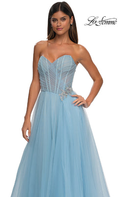 Woman in the La Femme 32789 strapless long prom ball gown, featuring light blue tulle, a sweetheart bodice, and rhinestone floral waist detail, standing against a white background.