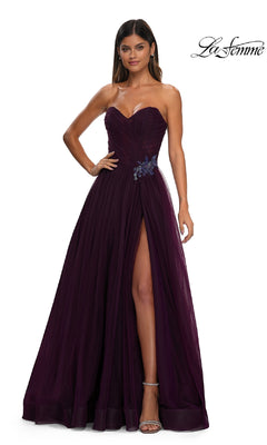 A woman models the La Femme 32789 Strapless Long Prom Ball Gown in deep purple with a sweetheart bodice, thigh-high slit, and rhinestone floral waist detail, standing against a white background.