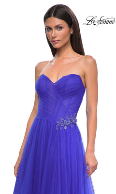 A woman wears the La Femme 32789 strapless long prom ball gown in royal blue, featuring a pleated sweetheart bodice and jeweled rhinestone floral waist detail. "La Femme" logo appears in the upper right corner.
