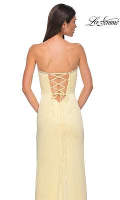 A woman poses with her back to the camera in the Classic Strapless Long Prom Dress: La Femme 32799, a light yellow gown with lace-up back detailing, set against a white background. The La Femme logo appears in the top right corner.