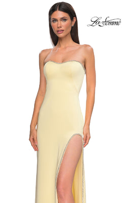 A woman models the Classic Strapless Long Prom Dress: La Femme 32799 in pale yellow with a high slit and silver trim, posing against a plain white background with the "La Femme" logo at the top right.