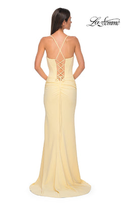 Woman in a long, pale yellow Lace-Up Open-Back Long Prom Dress (La Femme 32802) with thin straps and crisscross lace-up back, standing with her back to the camera.