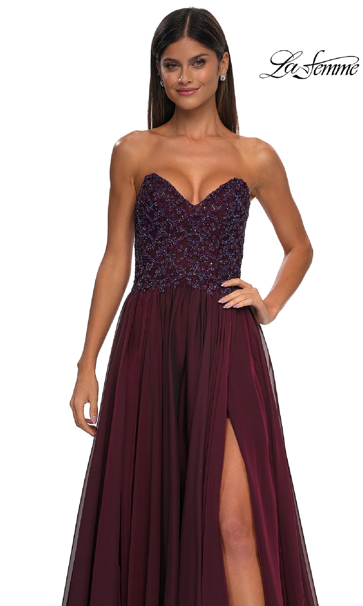 Woman in a strapless burgundy La Femme 32804 A-line prom dress with beaded bodice and thigh-high slit, standing against a white background. 