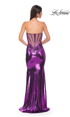 A woman models the La Femme 32806 Strapless Long Metallic Prom Dress in purple, featuring a sheer structured back and fitted silhouette, as she faces away from the camera. The La Femme logo appears in the top right corner.