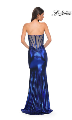 A woman wears the La Femme 32806 Strapless Long Metallic Prom Dress, featuring a mermaid silhouette and sheer corset-style back panel. The fitted, floor-length formal dress displays the "La Femme" logo in the top right corner.