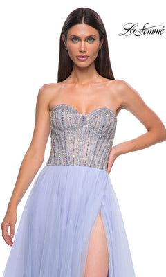 A woman wearing the La Femme 32811 Strapless Long Prom Ball Gown, featuring a beaded sweetheart corset in silver and lavender, tulle skirt, and thigh-high slit, stands against a white background.